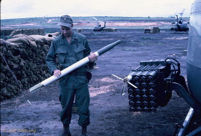 Ernie Kramer
Bob Kelly Photo

D/227. Camp Evans. Ernie Kramer checking a 2.75 rocket by ARA ship. Fins opened for stability after the rocket was fired.
