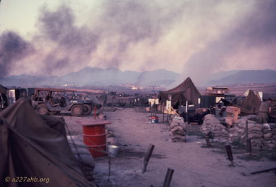 D/227 the morning after the ammo dump explosion
Bob Kelly Photo

The ammo dump blew all night. This photo is of the D/227 company street. Maibox on ground. Burnt and damaged tents. "Guns 227" used to be on right.

