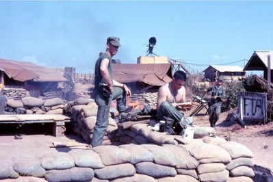Leaving Phan Thiet
Jim Gray Photo

Mid January 1968, Co. A 227th AHB has been ordered to join the rest of the Division at LZ English. Jay Dirnberger can be seen in what remains of one of the Pilots' tents as the Company area is broken down for the move north.. Mike Lane sits on the sand bag perimeter of the tent while Roland Haight carries a lounge chair from his hootch that was located behind the F.T.A. sign.
